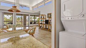A modern kitchen with a granite countertop, a ceiling fan, and a built-in washer and dryer.