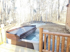 Un jacuzzi en una terraza de madera con vista a un bosque.