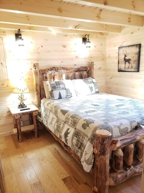 A rustic wooden bedroom with a bed, a nightstand, and a lamp. - King of Hearts. Secluded Hocking Hills cabin! (Rockbridge)