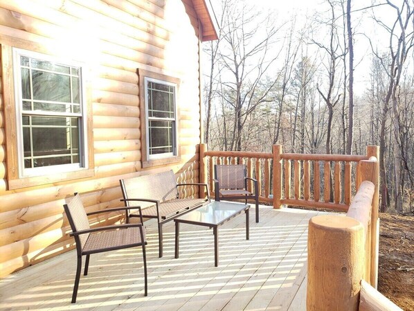 A wooden cabin with a deck featuring two chairs and a table. - King of Hearts. Secluded Hocking Hills cabin! (Rockbridge)