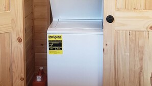 A compact laundry room with a front-loading washer and dryer, wooden walls, and a door. - King of Hearts.  Secluded Hocking Hills cabin! (Rockbridge)