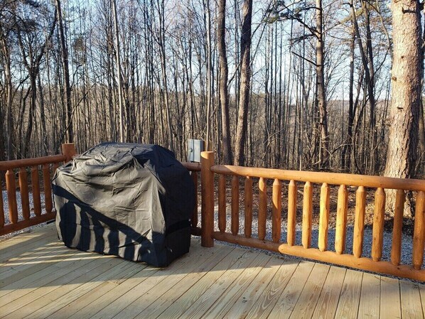 A wooden deck with a covered object and a wooden railing.