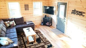A cabin interior with a sofa, coffee table, TV, and fireplace. - King of Hearts.  Secluded Hocking Hills cabin! (Rockbridge)