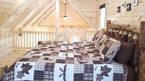 A cozy attic bedroom with a wooden ceiling, a quilted bedspread, and a ceiling fan. - King of Hearts. Secluded Hocking Hills cabin! (Rockbridge)