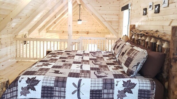 A cozy attic bedroom with a wooden ceiling, a quilted bedspread, and a ceiling fan. - King of Hearts.  Secluded Hocking Hills cabin! (Rockbridge)
