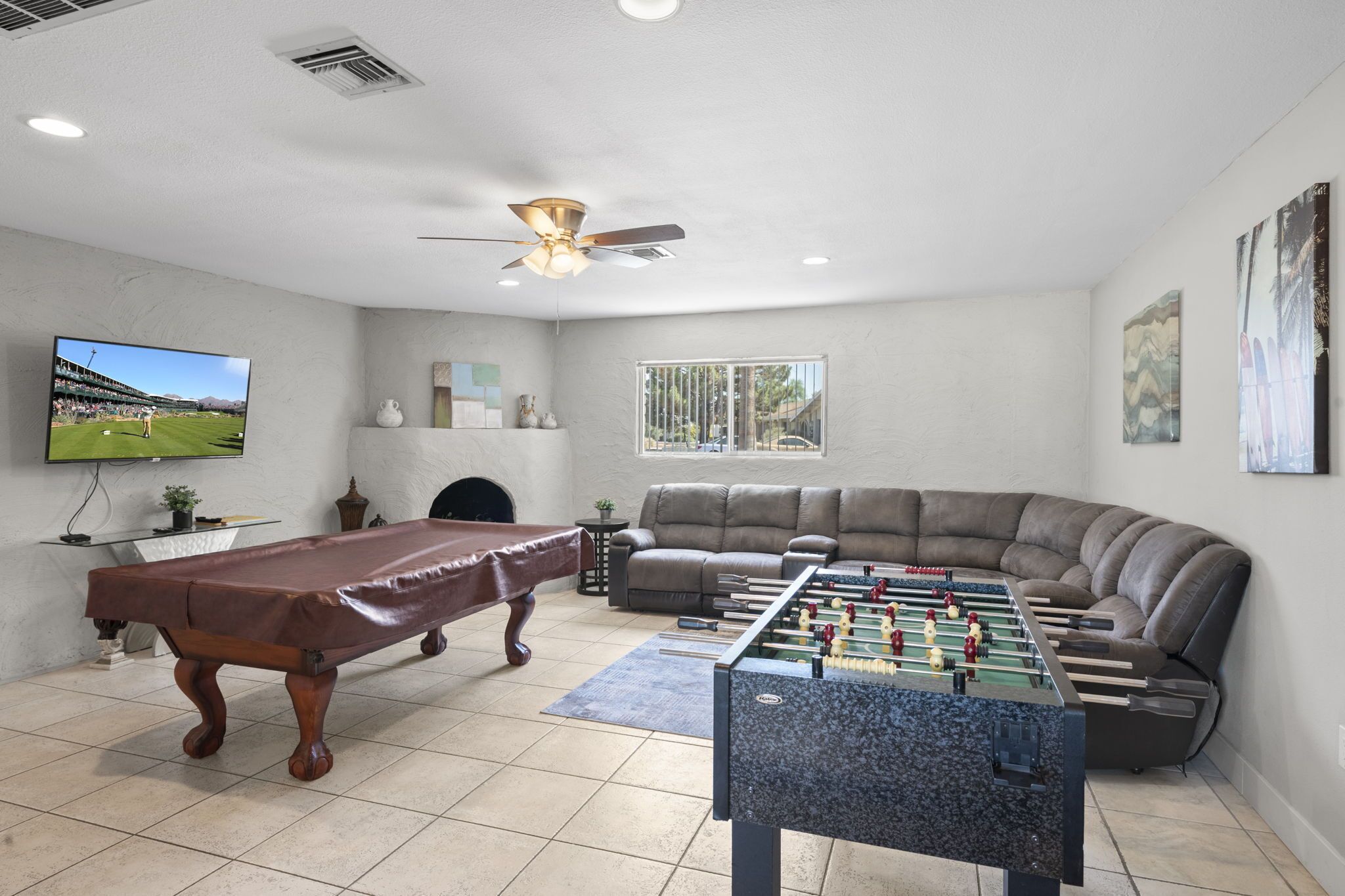 A living room with a pool table, foosball table, and a large sofa.