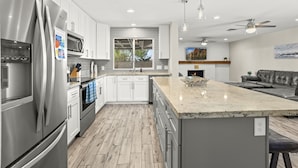 Una cocina moderna con electrodomésticos de acero inoxidable, una isla grande e iluminación colgante.