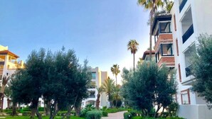 Un sendero bordeado de vegetación y edificios con balcones.
