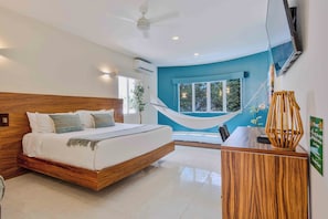 A modern bedroom with a wooden bed, a desk, a hammock, and a TV.