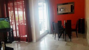 Ein Zimmer mit Essbereich, Fernseher und einem Fenster mit roten Vorhängen.