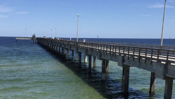A pier extending into clear blue water with a view of the ocean in the distance. - HUGE 4BR/3BA! Pool, Beach & Boat Slip! 4 Car Garage  (Corpus Christi)