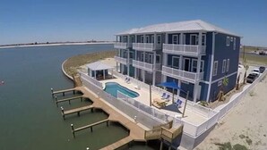 A multi-story building with a pool, located near a body of water. - HUGE 4BR/3BA! Pool, Beach & Boat Slip! 4 Car Garage  (Corpus Christi)