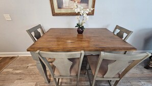 Un tavolo da pranzo in legno con quattro sedie, un vaso con fiori e un quadro appeso al muro.