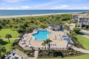 Un complexe hôtelier doté d’une piscine, de chaises longues et offrant une vue sur la plage.