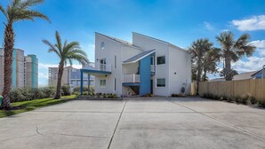 Une maison moderne à deux étages, avec un mur d’accent bleu, un balcon et une cour arrière clôturée.