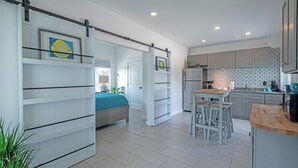 Une cuisine moderne dotée d’un îlot central, de meubles de rangement intégrés et d’un coin repas avec des tabourets.
