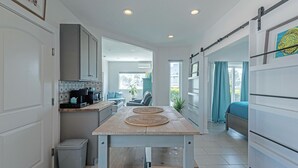 Une cuisine moderne dotée d’un îlot central, d’un coin repas et d’une chambre avec une porte coulissante.