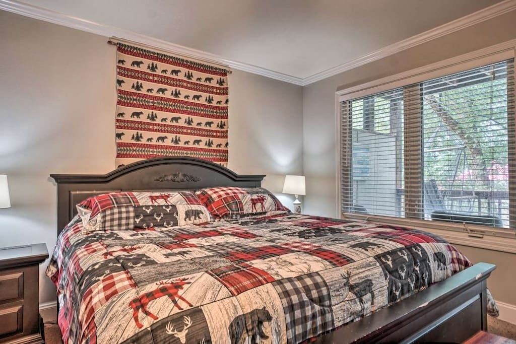 Un dormitorio con una cama grande, cabecera con diseño de oso, ventana con persianas y un tapiz decorado con estampados de osos.