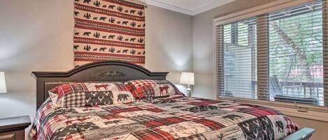 Un dormitorio con una cama grande, cabecera con diseño de oso, ventana con persianas y un tapiz decorado con estampados de osos.
