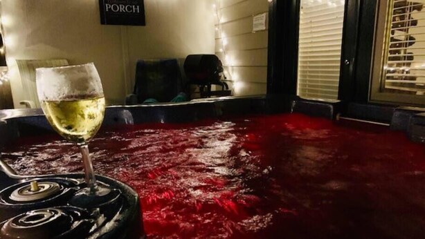 Een kuip met warm, rood water, een wijnglas en een bordje met de tekst 'PORCH'.