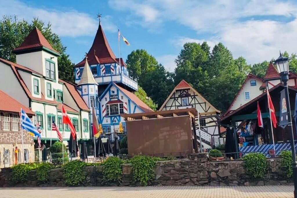 A traditional European village with colorful buildings, a prominent tower, and flags.