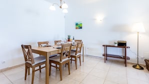 A dining area with a wooden table and chairs, a pendant light, a small table with a lamp, and a painting on the wall. - CoolHouses Algarve Lagos | Casa Evasion (Lagos)