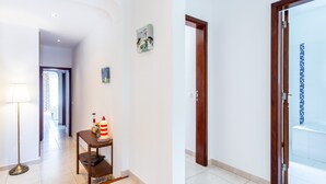 A hallway with a lamp, a small table with a red and white striped object, and a door leading to a bathroom with blue mosaic tiles. - CoolHouses Algarve Lagos | Casa Evasion (Lagos)