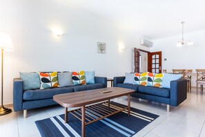 Un salon moderne avec deux canapés, une table basse et un coin repas comprenant des chaises et une table.