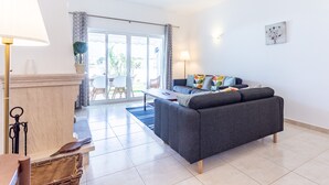A modern living room with a grey sofa, a coffee table, a lamp, and a dining area with a table and chairs. - CoolHouses Algarve Lagos | Casa Evasion (Lagos)
