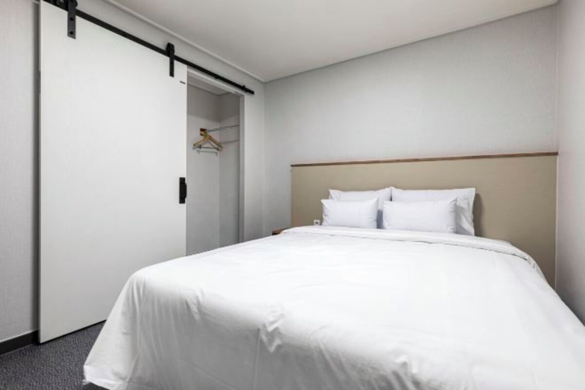 Een hotelkamer met een bed, een kledingkast en een deur.