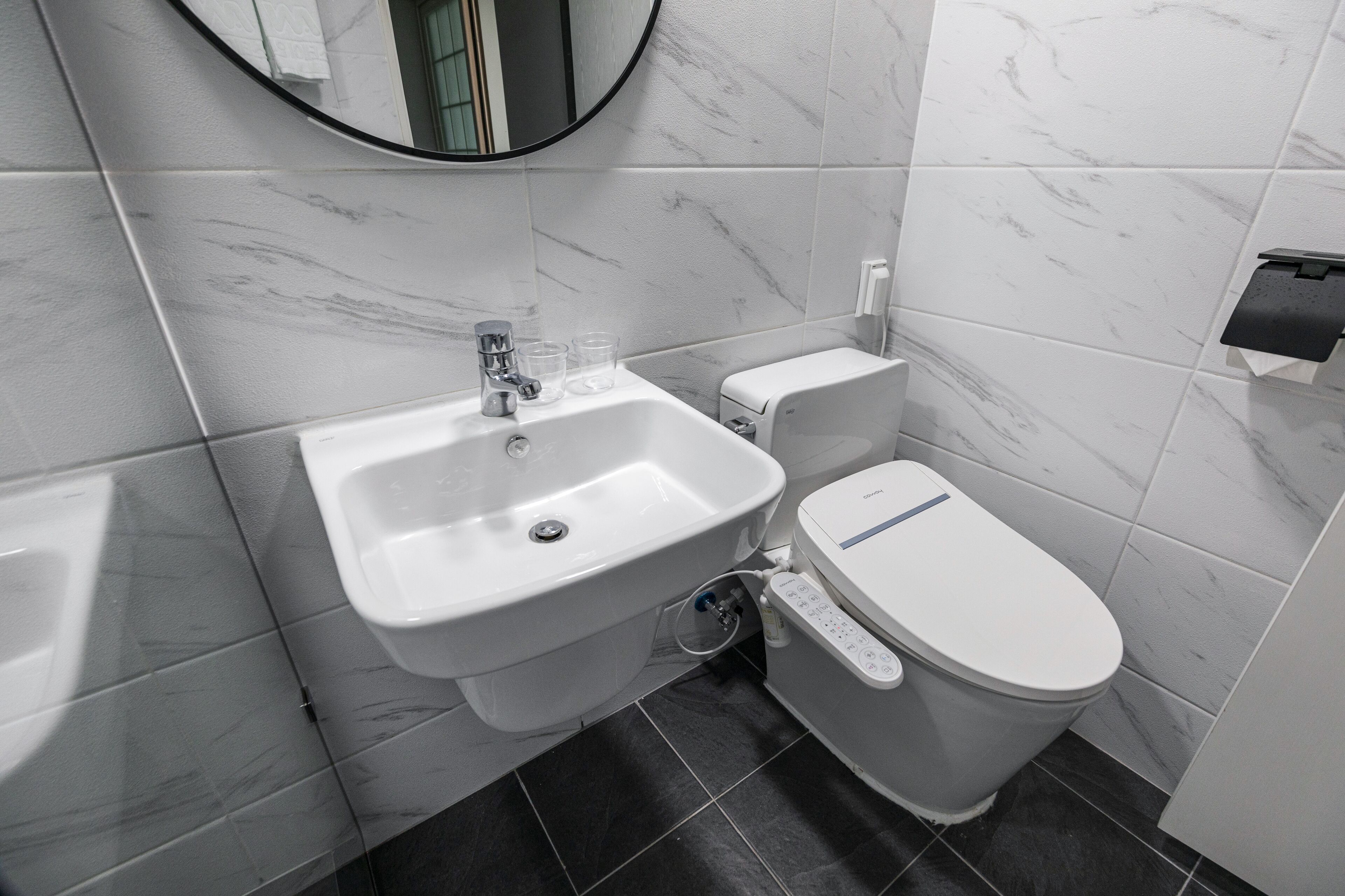 A modern bathroom with a white sink, toilet, and marble tiles.