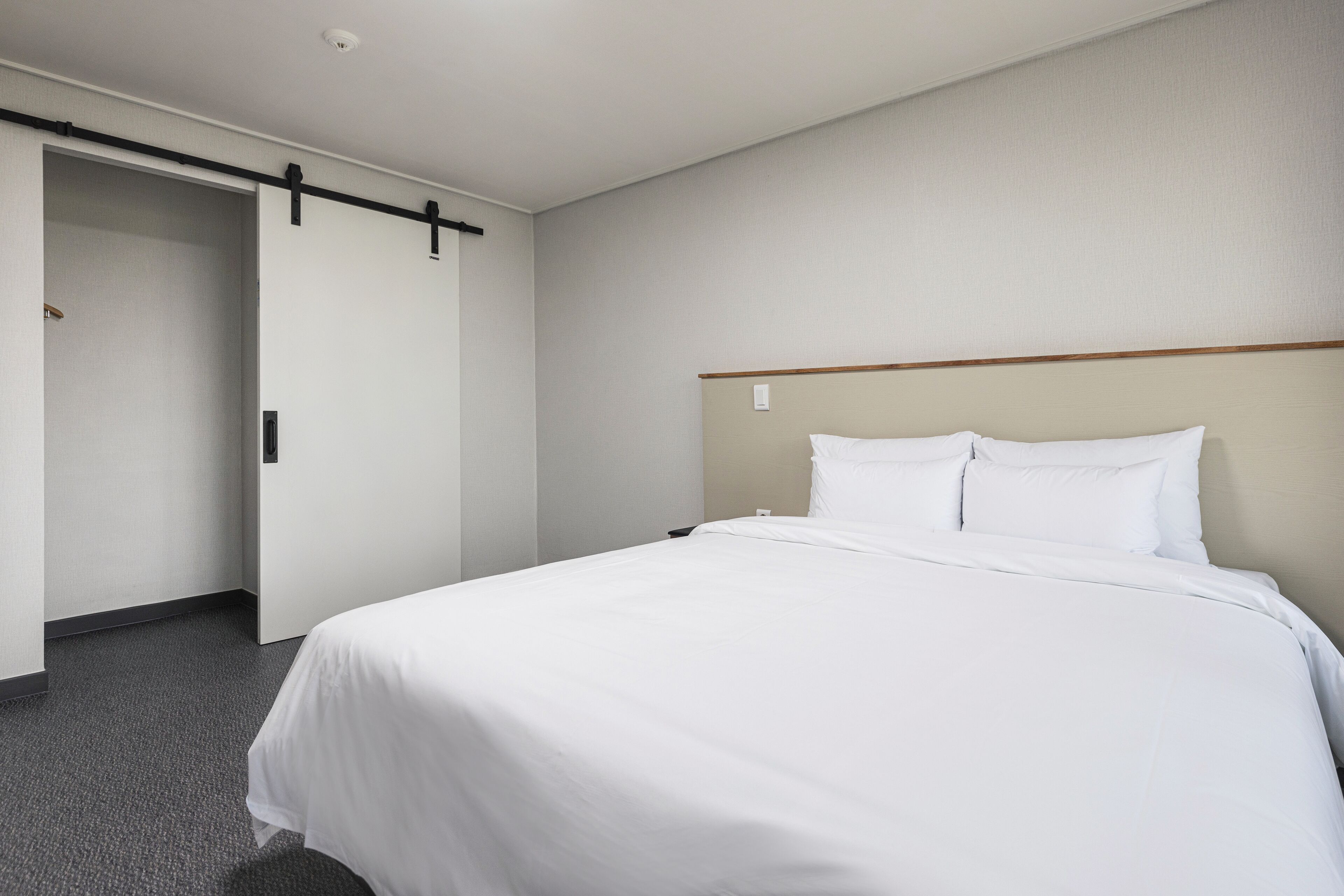 A hotel room with a bed, a wardrobe, and a door.