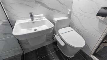 A modern bathroom with a white sink, a toilet, and a shower area.
