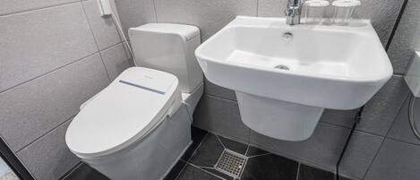 Une salle de bain moderne équipée de toilettes, d’un lavabo et d’une douche.