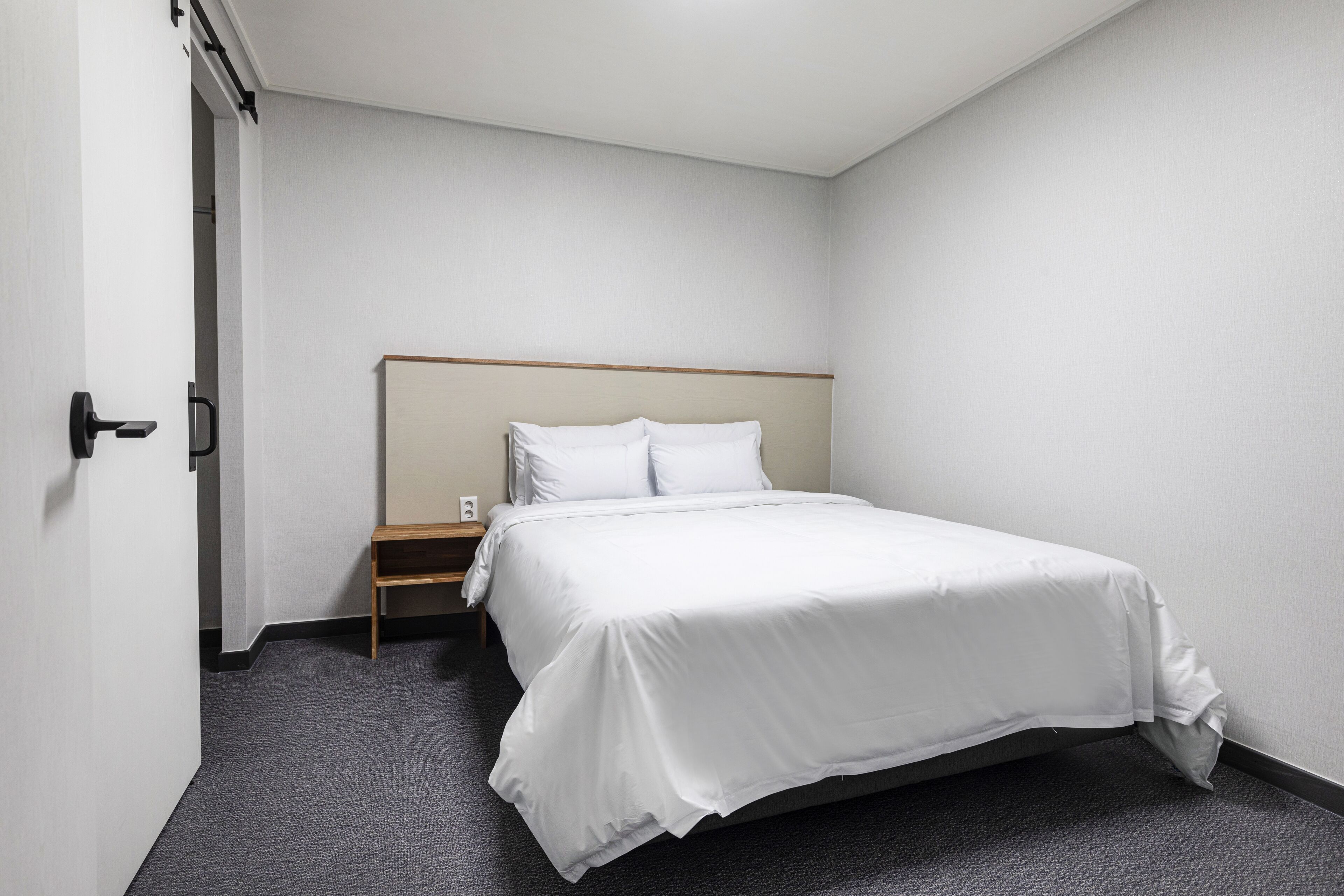 Una habitación de hotel con una cama individual, una mesita de noche y una puerta.
