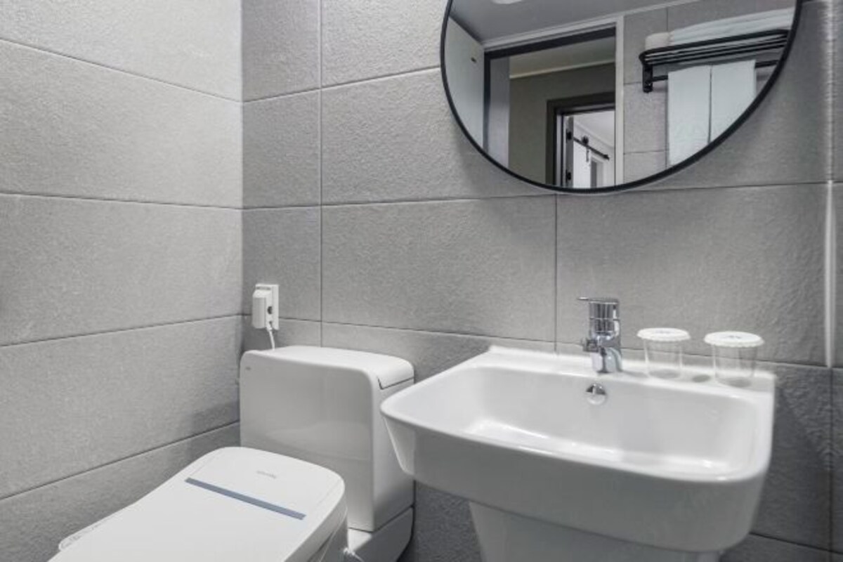 Een moderne badkamer met toilet, wastafel en spiegel.