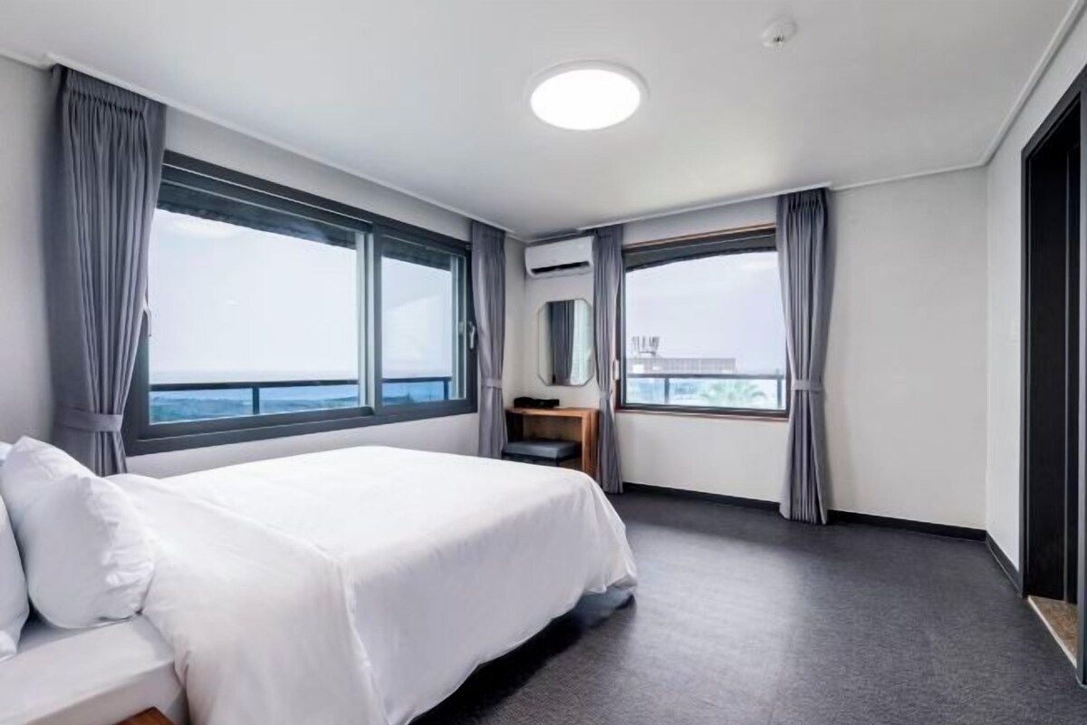 Ein modernes Hotelzimmer mit einem großen Bett, einem Schreibtisch und Blick auf das Meer.