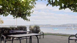 Un parc au bord de l’eau, doté de bancs et offrant une vue sur les voiliers qui naviguent.