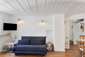 Een kamer met een bed, een aan de muur bevestigde televisie, een ventilator en een houten vloer.