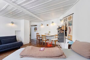 Ein modernes Wohnzimmer mit einer Couch, einem Essbereich mit Stühlen und einer Wand mit Lehrmaterialien.
