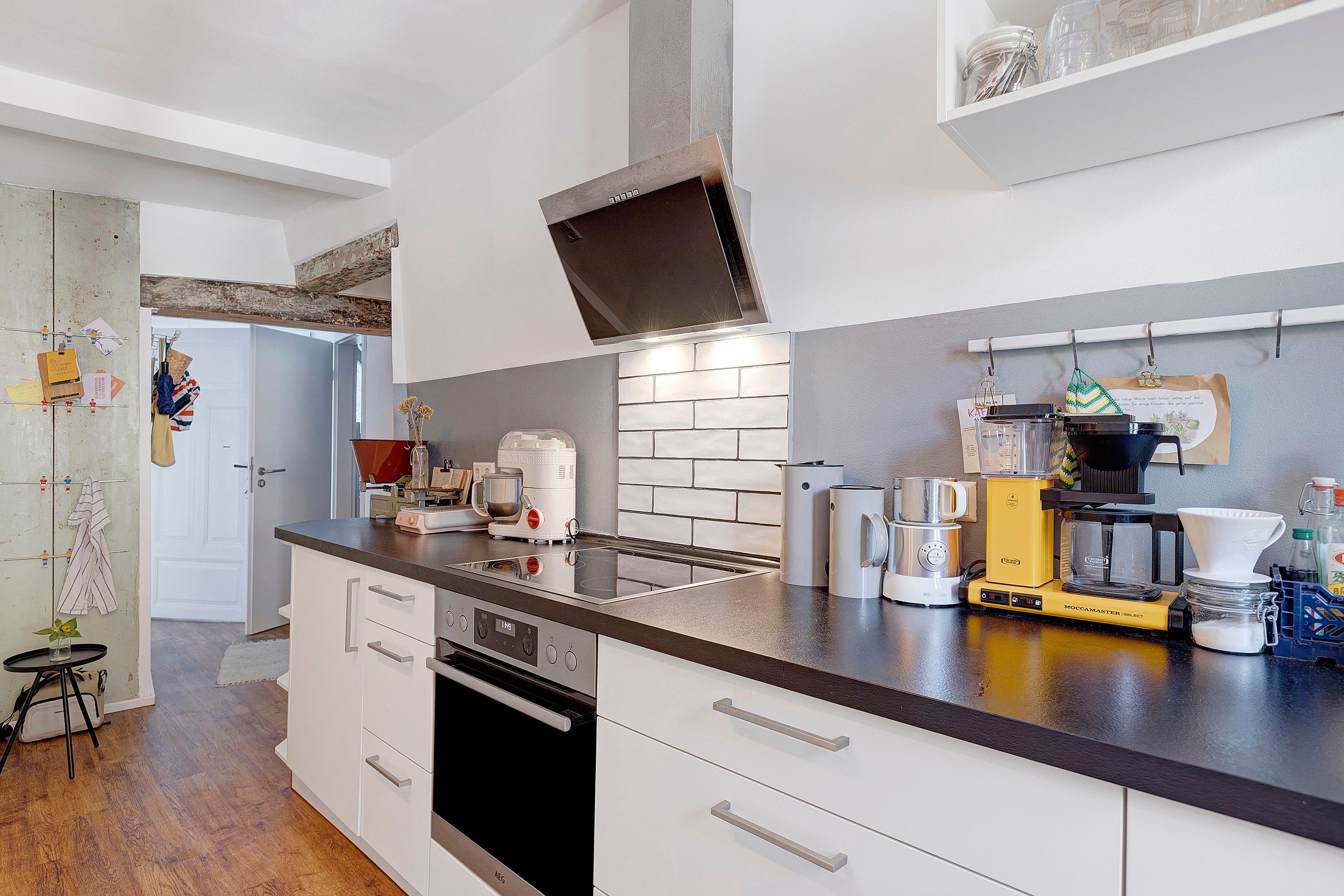 Una cocina moderna con horno empotrado, cafetera y hervidor sobre la encimera.