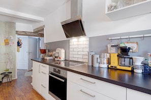 Una cocina moderna con horno empotrado, cafetera y hervidor sobre la encimera.