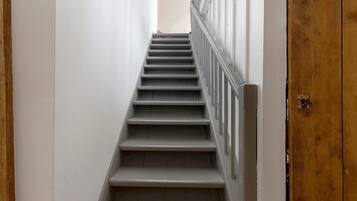 Una escalera estrecha con baranda de madera y paredes blancas.