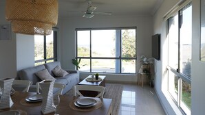 Un salon moderne avec un canapé, une table à manger et de grandes fenêtres.