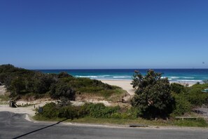 A coastal road leading to a beach with clear skies. - Beachfront Views - Sleeps 6 comfortably + Pets welcomed! (Blueys Beach)
