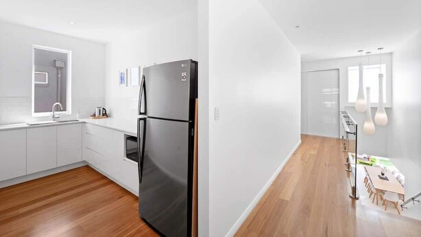 Eine moderne Küche mit weißen Schränken, einem schwarzen Kühlschrank und Holzboden.