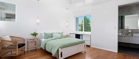 A modern bedroom with a bed, bedside tables, a chair, and a large window.