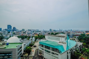 A cityscape with modern buildings, including a prominent dome structure and a building with a green roof. - Warm and Cozy Studio at Menteng Park Apartment (Jakarta)