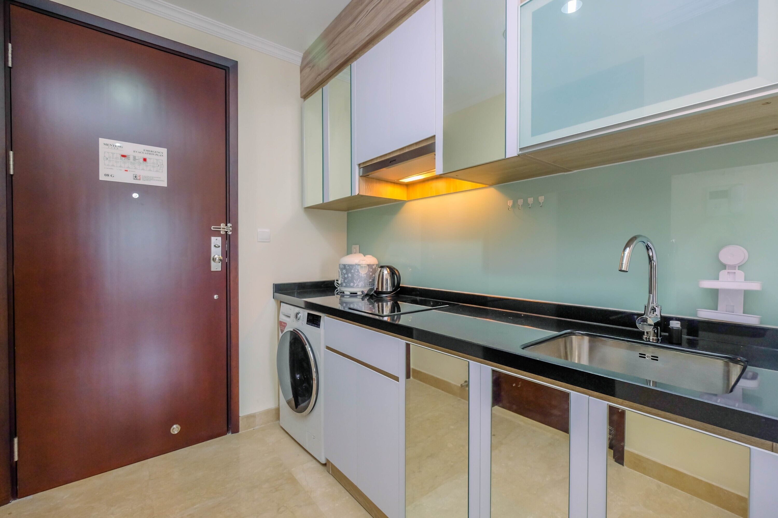 A compact kitchen with a washing machine, a sink, and cabinets.