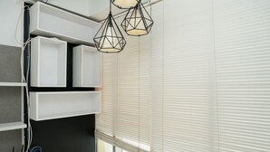 Una habitación moderna con estanterías empotradas, una ventana con persianas y una lámpara colgante.